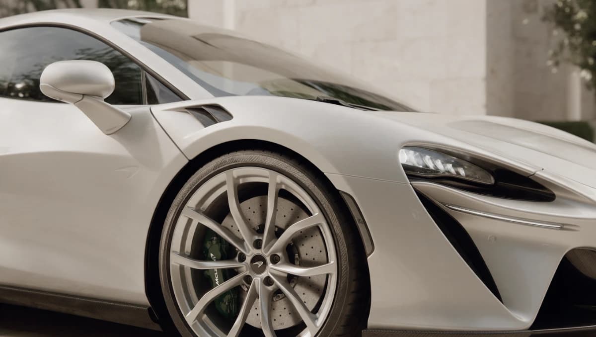 Close view of a white sports car’s sculpted front quarter and wheel
